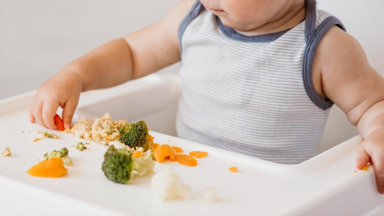Bayi tertarik pada makanan dan mengulurkan tangan ke arah mpasi