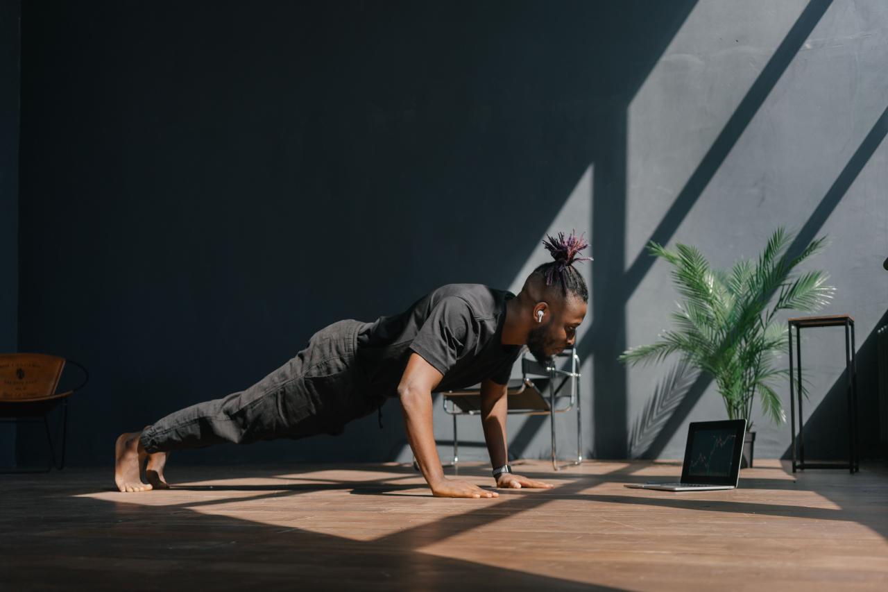 Pria melakukan push-up dengan posisi tubuh lurus dari kepala hingga tumit di atas matras latihan.
