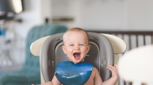 Bayi duduk di baby chair dengan MPASI di depannya