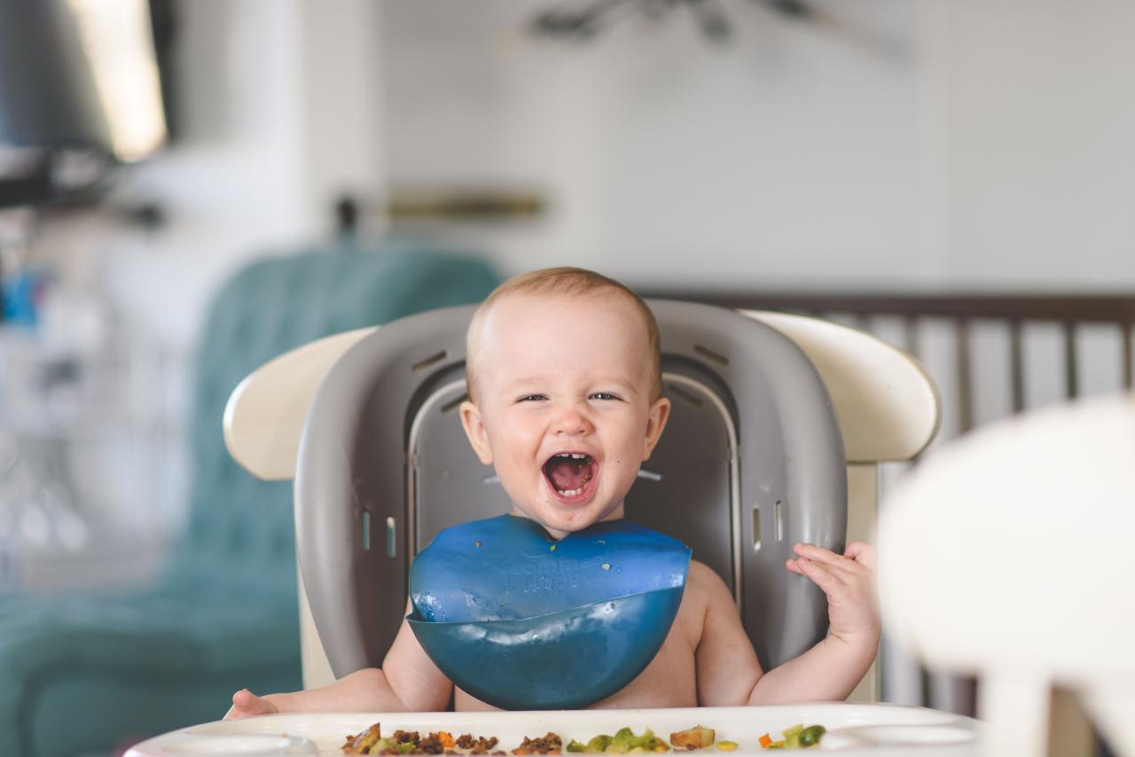 Bayi duduk di baby chair dengan MPASI di depannya